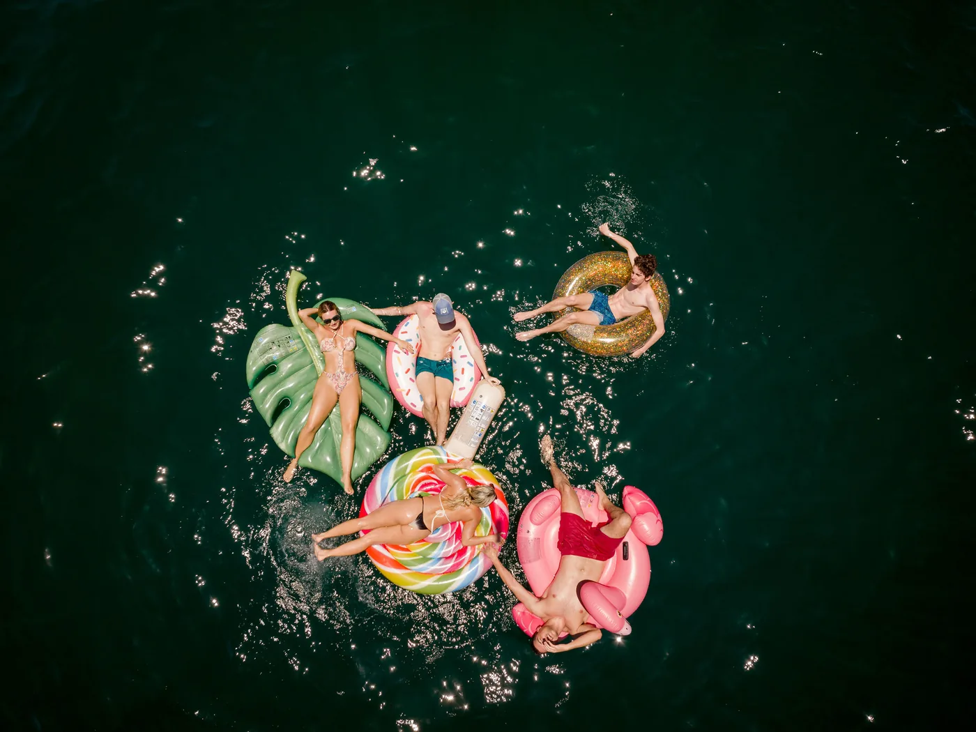 Aerial view of guests floating on inflatables in clear water beside an Ocean Club charter, Costa Rica